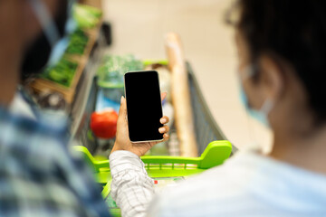 Family Using Grocery Shopping Mobile Application On Smartphone In Supermarket