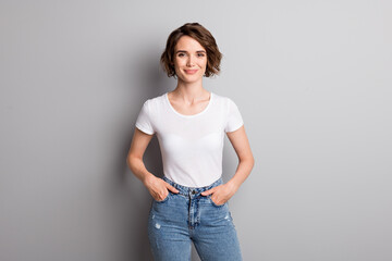 Photo of young attractive cheerful girl wear casual outfit hands in pocket confident smile isolated over grey color background