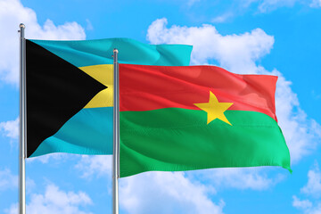 Burkina Faso and Bahamas national flag waving in the windy deep blue sky. Diplomacy and international relations concept.