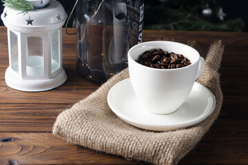 White cup with coffee beans stands on a wooden table