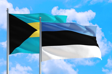 Estonia and Bahamas national flag waving in the windy deep blue sky. Diplomacy and international relations concept.
