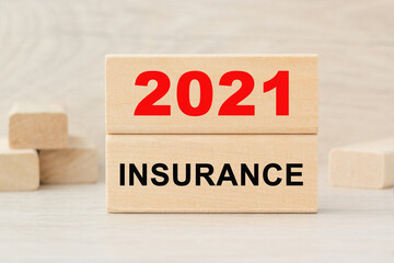 the word 2021 INSURANCE is written on a wooden cubes structure. Cube on a bright background. Can be used for business, marketing, financiaL, INSURANCE concept. Selective focus.