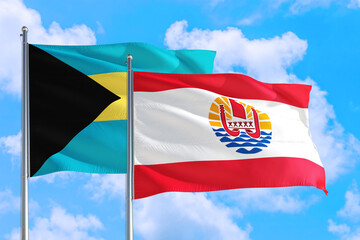 French Polynesia and Bahamas national flag waving in the windy deep blue sky. Diplomacy and international relations concept.