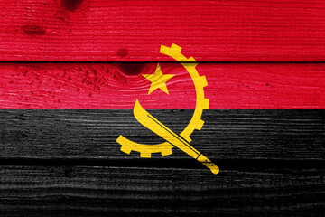 Angola flag painted on old wood plank background. Brushed natural light knotted wooden board...