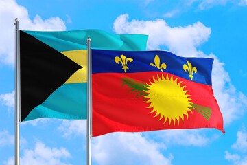 Guadeloupe and Bahamas national flag waving in the windy deep blue sky. Diplomacy and international relations concept.