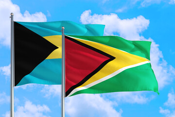 Guyana and Bahamas national flag waving in the windy deep blue sky. Diplomacy and international relations concept.