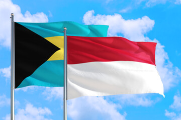 Indonesia and Bahamas national flag waving in the windy deep blue sky. Diplomacy and international relations concept.