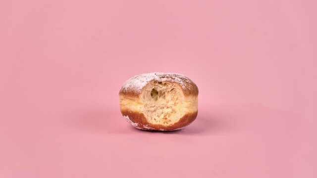 Stop motion sweet doughnut with filling. Half-eaten food., in the context of. On a pink background.