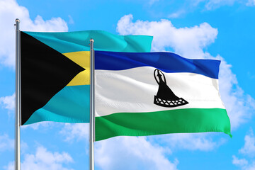Lesotho and Bahamas national flag waving in the windy deep blue sky. Diplomacy and international relations concept.