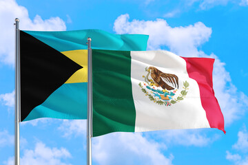 Mexico and Bahamas national flag waving in the windy deep blue sky. Diplomacy and international relations concept.