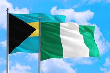Nigeria and Bahamas national flag waving in the windy deep blue sky. Diplomacy and international relations concept.