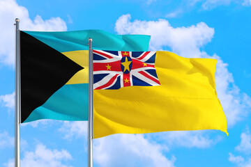 Niue and Bahamas national flag waving in the windy deep blue sky. Diplomacy and international relations concept.