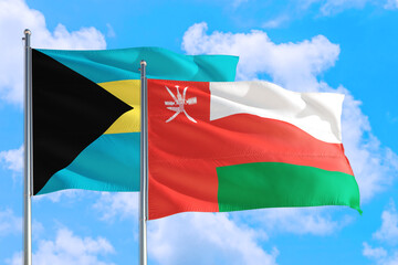 Oman and Bahamas national flag waving in the windy deep blue sky. Diplomacy and international relations concept.