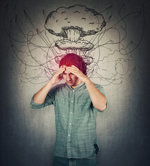Bewildered man head explosion concept. Guy suffering headache, hands to forehead, looking down...