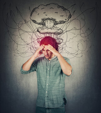 Bewildered man head explosion concept. Guy suffering headache, hands to forehead, looking down depressed. People mental health concept. Stress causes migraine and anxiety problems, dementia disease.