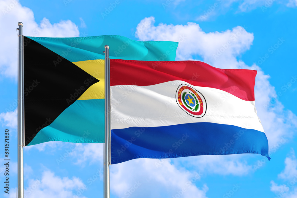 Wall mural Paraguay and Bahamas national flag waving in the windy deep blue sky. Diplomacy and international relations concept. - Wall murals
