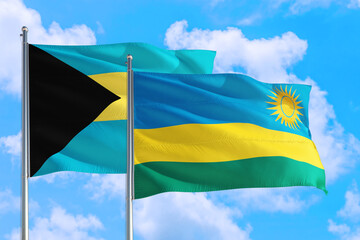 Rwanda and Bahamas national flag waving in the windy deep blue sky. Diplomacy and international relations concept.