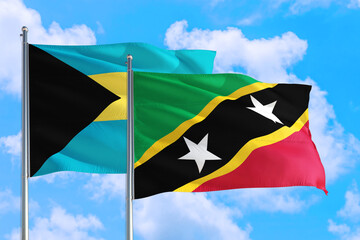 Saint Kitts And Nevis and Bahamas national flag waving in the windy deep blue sky. Diplomacy and international relations concept.