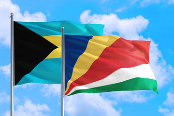Seychelles and Bahamas national flag waving in the windy deep blue sky. Diplomacy and international relations concept.