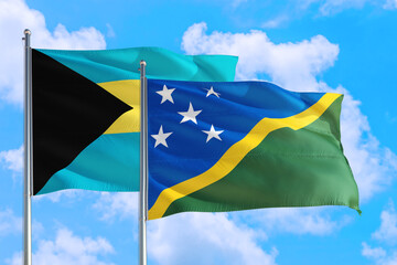 Solomon Islands and Bahamas national flag waving in the windy deep blue sky. Diplomacy and international relations concept.
