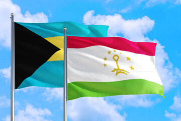 Tajikistan and Bahamas national flag waving in the windy deep blue sky. Diplomacy and international relations concept.