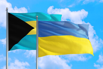 Ukraine and Bahamas national flag waving in the windy deep blue sky. Diplomacy and international relations concept.