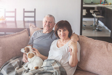 Obraz na płótnie Canvas Happy elderly couple sitting on sofa at home