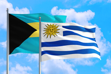 Uruguay and Bahamas national flag waving in the windy deep blue sky. Diplomacy and international relations concept.