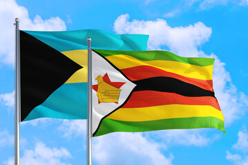 Zimbabwe and Bahamas national flag waving in the windy deep blue sky. Diplomacy and international relations concept.