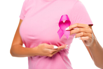 Cropped view of woman holding ribbon of breast cancer awareness and touching breast on blurred background isolated on white