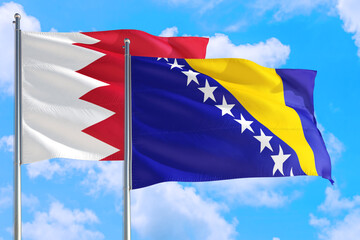 Bosnia Herzegovina and Bahrain national flag waving in the windy deep blue sky. Diplomacy and international relations concept.