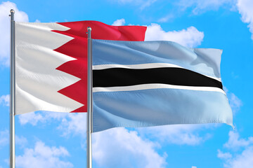 Botswana and Bahrain national flag waving in the windy deep blue sky. Diplomacy and international relations concept.