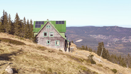 Retro toned picture of mountain hut with solar panels on roof.