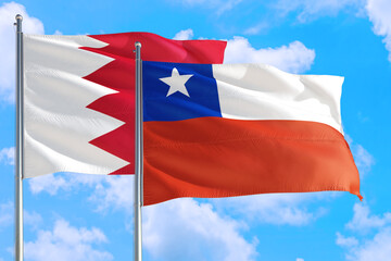 Chile and Bahrain national flag waving in the windy deep blue sky. Diplomacy and international relations concept.