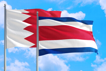 Costa Rica and Bahrain national flag waving in the windy deep blue sky. Diplomacy and international relations concept.