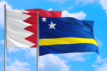 Curacao and Bahrain national flag waving in the windy deep blue sky. Diplomacy and international relations concept.