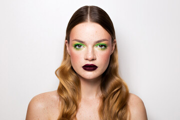 Fototapeta premium Beauty portrait of a girl with freckles and a creative make-up. Burgundy matte lipstick on the lips.