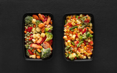 Frozen food vegetables in plastic containers on a black background. View from above.