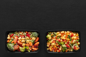 Frozen sliced vegetables salad in containers on a black background. Space for text. Top view, flat lay.