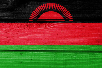 Malawi flag painted on old wood plank background. Brushed natural light knotted wooden board...