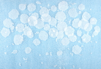 White round plastic foam sheet pieces on blue background. Winter snowfall concept. Torn foam polyethylene transparent pieces as snowflakes.