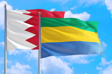 Gabon and Bahrain national flag waving in the windy deep blue sky. Diplomacy and international...