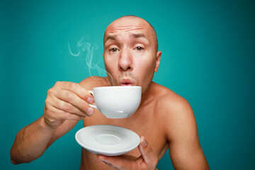 Funny naked bald man drinking coffee isolated on green background