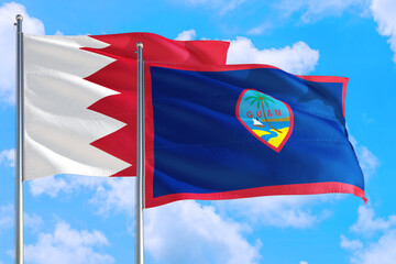 Guam and Bahrain national flag waving in the windy deep blue sky. Diplomacy and international relations concept.