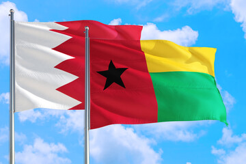 Guinea and Bahrain national flag waving in the windy deep blue sky. Diplomacy and international relations concept.