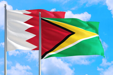 Guyana and Bahrain national flag waving in the windy deep blue sky. Diplomacy and international relations concept.