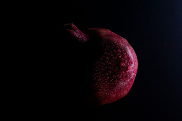 pomegranate with water drops on black background