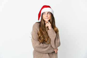Caucasian girl with christmas hat isolated on white background having doubts and thinking