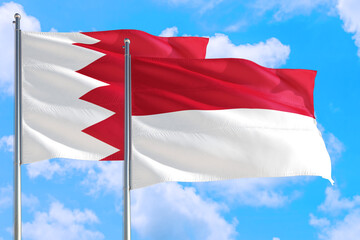 Indonesia and Bahrain national flag waving in the windy deep blue sky. Diplomacy and international relations concept.