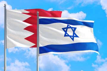 Israel and Bahrain national flag waving in the windy deep blue sky. Diplomacy and international relations concept.